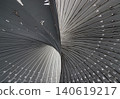 A sweeping, monochromatic vortex of metallic ribs twists elegantly across the frame, dividing it with a sinuous curve. Countless slender slats radiate outward in a mesmerizing pattern. To the left, 140619217