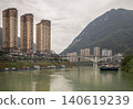 Along the emerald currents of the Wujiang River in Pengshui, Chongqing, towering skyscrapers stand like silent sentinels against a massive, mist-veiled mountain; in the distance, a graceful arched 140619239