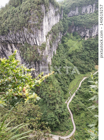 China Wulong Karst National Geology Park, a UNESCO World Natural Heritage Site. Sheer limestone cliffs rise straight up from the canyon floor. Water erosion shaped these massive vertical stone crags China Wulong Karst National Geology Park, a UNESCO World Natural Heritage Site. Sheer limestone cliffs rise straight up from the canyon floor. Water erosion shaped these massive vertical stone crags 140619257