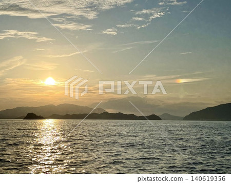 A parhelion appearing on the sea at dawn, with the silhouettes of beautiful islands. A parhelion appearing on the sea at dawn, with the silhouettes of beautiful islands. 140619356