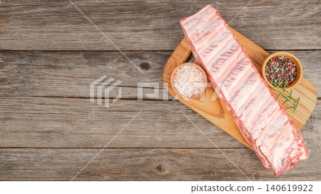 Pork ribs raw rack on wooden board with spices, butcher meat preparation on rustic table 140619922