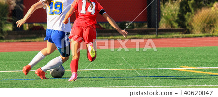 Two Female Soccer Players Chase the Ball During a Game 140620047