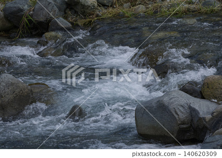 The spray of water from the raging stream flowing between the rocks The spray of water from the raging stream flowing between the rocks 140620309