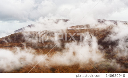 Mist drifts across a brown, heather-covered mountainside under a bright sky. Mist drifts across a brown, heather-covered mountainside under a bright sky. 140620948