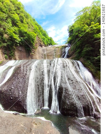Fukuroda Falls in Ibaraki Prefecture. A magnificent sight of a four-tiered waterfall cascading down amidst the refreshing greenery of early summer, making it a popular tourist spot in Japan. Fukuroda Falls in Ibaraki Prefecture. A magnificent sight of a four-tiered waterfall cascading down amidst the refreshing greenery of early summer, making it a popular tourist spot in Japan. 140621687