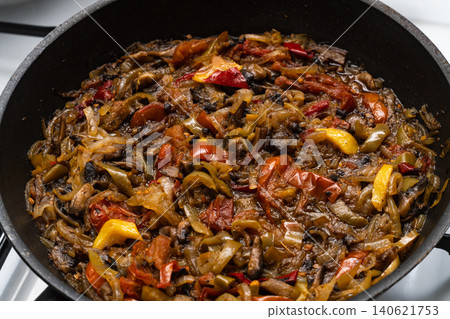 A well-fried stew of vegetables and mushrooms in vegetable oil in a black frying pan. Cooking at home as an element of home comfort A well-fried stew of vegetables and mushrooms in vegetable oil in a black frying pan. Cooking at home as an element of home comfort 140621753