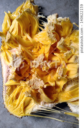 Top view of halved jackfruit with vibrant yellow segments and sticky fibers. 140622159