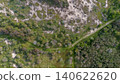 Aerial top-down view of a winding dirt track through green forest vegetation and rolling sand dunes, creating a natural abstract texture in a Dutch coastal nature reserve. 140622620