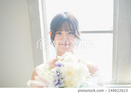 A Japanese woman in a wedding dress gazes at her bouquet. A Japanese woman in a wedding dress gazes at her bouquet. 140622623
