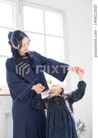 一位微笑的日本女孩牽著媽媽的手。 一位微笑的日本女孩牽著媽媽的手。 140622685