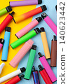 Colorful disposable vape pens scattered on vibrant yellow and blue background 140623442