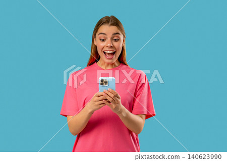 Shocked woman with smartphone on blue studio with open mouth. Amazed lady, app 140623990