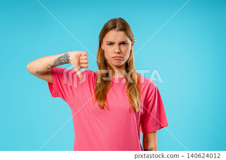 Pretty Young Woman With Dislike Sign. Stylish Lady Showing Thumbs-Down on Blue Pretty Young Woman With Dislike Sign. Stylish Lady Showing Thumbs-Down on Blue 140624012