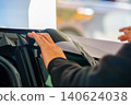 A car wrapping specialist applies a polyurethane film to the car. Detailer PPF 140624038