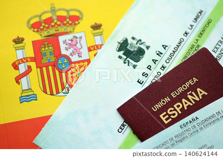 Spanish passport lies on citizenship or naturalization documents on flag of Spain Spanish passport lies on citizenship or naturalization documents on flag of Spain 140624144