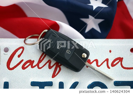 Remote control car keys on California license plate on US flag. Car driving in California Remote control car keys on California license plate on US flag. Car driving in California 140624304