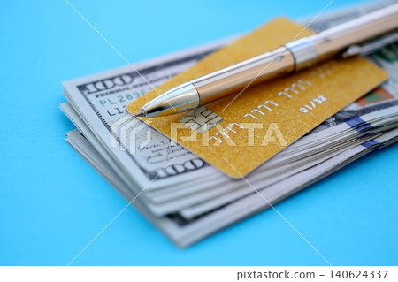 Credit card and pen with US dollar currency money bills banknotes on light blue background Credit card and pen with US dollar currency money bills banknotes on light blue background 140624337