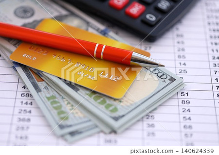 Credit card and pen with US dollar currency money bills banknotes on calculations document 140624339