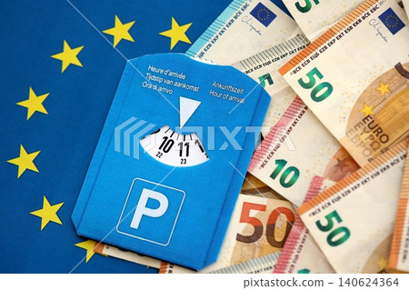 European parking disc with time dial on many euro money bills banknotes on flag of European Union European parking disc with time dial on many euro money bills banknotes on flag of European Union 140624364