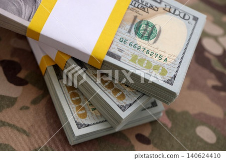 Three packs of ten thousand US dollar bills on camouflage background. Packs of hundred dollar bills Three packs of ten thousand US dollar bills on camouflage background. Packs of hundred dollar bills 140624410