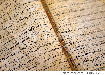 Pages of Al Quran Muslim old holy book on table in mosque. Details of arabic calligraphy in book Pages of Al Quran Muslim old holy book on table in mosque. Details of arabic calligraphy in book 140624548