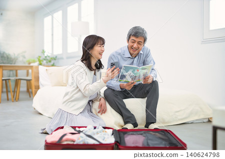 A smiling senior couple preparing for a trip. 140624798