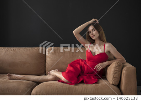 young beautiful woman sitting on a sofa near the window young beautiful woman sitting on a sofa near the window 140625138