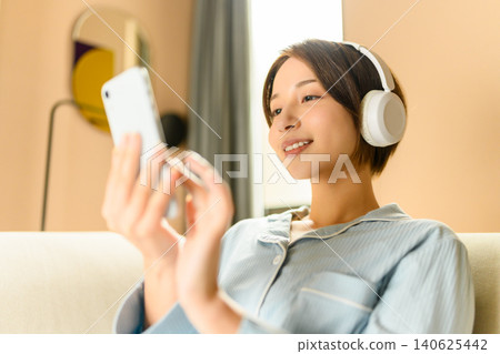A young woman listening to music with headphones A young woman listening to music with headphones 140625442