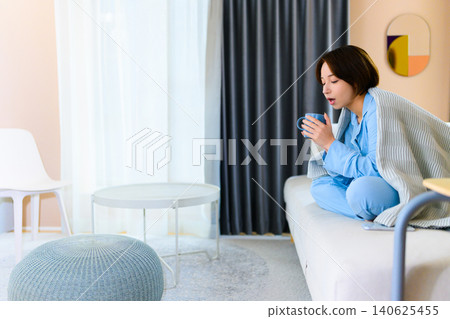 Woman drinking hot drink in room 140625455