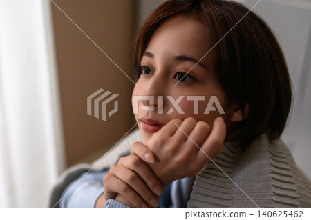 A woman rests her chin on her hand and looks out the window. A woman rests her chin on her hand and looks out the window. 140625462