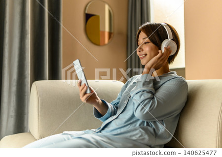 A woman listening to music with headphones A woman listening to music with headphones 140625477