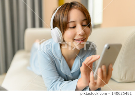 A young woman listening to music on the sofa A young woman listening to music on the sofa 140625491