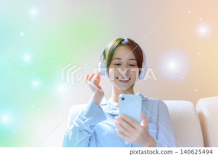 A woman listening to music with headphones while looking at her smartphone. 140625494
