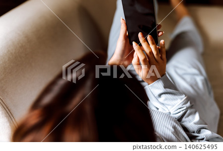 A woman operating a smartphone on the sofa A woman operating a smartphone on the sofa 140625495