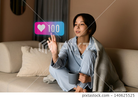 A woman relaxing on a sofa and drinking a beverage. 140625525