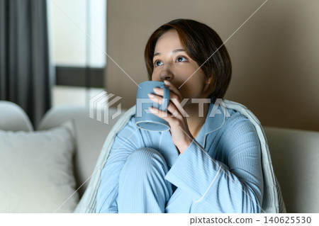 A woman warming herself with a mug. 140625530