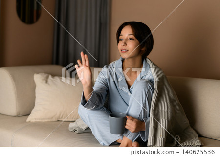 A woman relaxing on a sofa and drinking a beverage. A woman relaxing on a sofa and drinking a beverage. 140625536