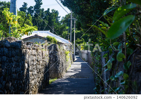 沖繩傳統村莊景象:一條狹窄的小巷,兩旁是石牆和白瓦屋頂的房子。 沖繩傳統村莊景象:一條狹窄的小巷,兩旁是石牆和白瓦屋頂的房子。 140626092