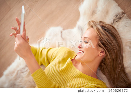 Tablet, smile and social media with woman on floor of home for browsing, communication or weekend free time. Tech, relax and happy young person in living room of apartment for download from above Tablet, smile and social media with woman on floor of home for browsing, communication or weekend free time. Tech, relax and happy young person in living room of apartment for download from above 140626572
