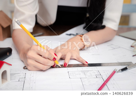 Female Architect working with pencil and ruler on blueprint. Architect engineer contractor design working drawing sketch plan blueprint and making architectural construction house building. Female Architect working with pencil and ruler on blueprint. Architect engineer contractor design working drawing sketch plan blueprint and making architectural construction house building. 140626839