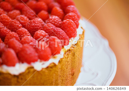 Plate, frosting and cheesecake with raspberries on table for sweet snack for tea time at home. Bakery, catering and closeup of gourmet dessert with crust, cream and fresh organic fruit in dining room Plate, frosting and cheesecake with raspberries on table for sweet snack for tea time at home. Bakery, catering and closeup of gourmet dessert with crust, cream and fresh organic fruit in dining room 140626849