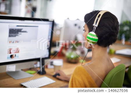 Business, designer and woman with headphones at computer screen in office for creative internship and web design. Employee, rear view and monitor for multimedia production and video animation at desk 140627036