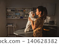 Focused Female Vet Lifts White Terrier Dog on Exam Table in Moody Clinic Setting 140628382