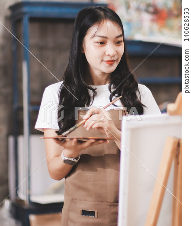 Female artist wears black hat posing near picture indoor the studio Female artist wears black hat posing near picture indoor the studio 140628553