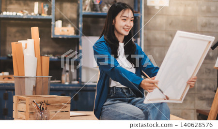 Female artist wears black hat posing near picture indoor the studio 140628576