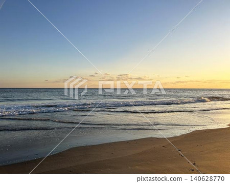 輕柔的海浪拍打著沙灘,夕陽西下,景色迷人。 輕柔的海浪拍打著沙灘,夕陽西下,景色迷人。 140628770
