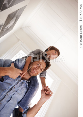 Father with boy on his shoulders, portrait and home with smile and love with single parent and happiness. Family, dad carrying son and childhood with fun and playing with joy and bonding together Father with boy on his shoulders, portrait and home with smile and love with single parent and happiness. Family, dad carrying son and childhood with fun and playing with joy and bonding together 140628790