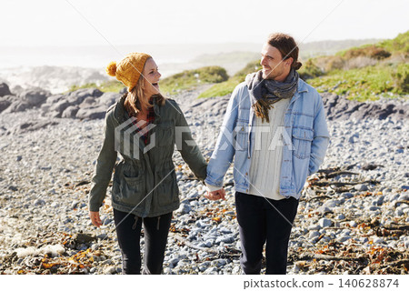 Holding hands, love and couple by ocean walking for bonding, romantic relationship and relax outdoors. Nature, travel and happy man and woman by sea for winter holiday, vacation and weekend together Holding hands, love and couple by ocean walking for bonding, romantic relationship and relax outdoors. Nature, travel and happy man and woman by sea for winter holiday, vacation and weekend together 140628874