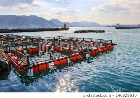 Fish farming cages floating in the blue sea near the Breakwater, Aquaculture in at Shimonoseki, Japan. Fish farming cages floating in the blue sea near the Breakwater, Aquaculture in at Shimonoseki, Japan. 140629630