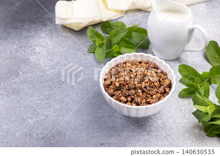 Chocolate granola bowl with fresh mint leaves and milk 140630535